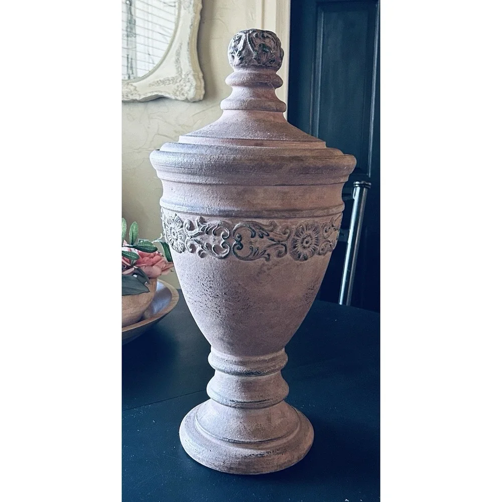 decorative terracotta urn with a distressed, rustic finish and a matching lid